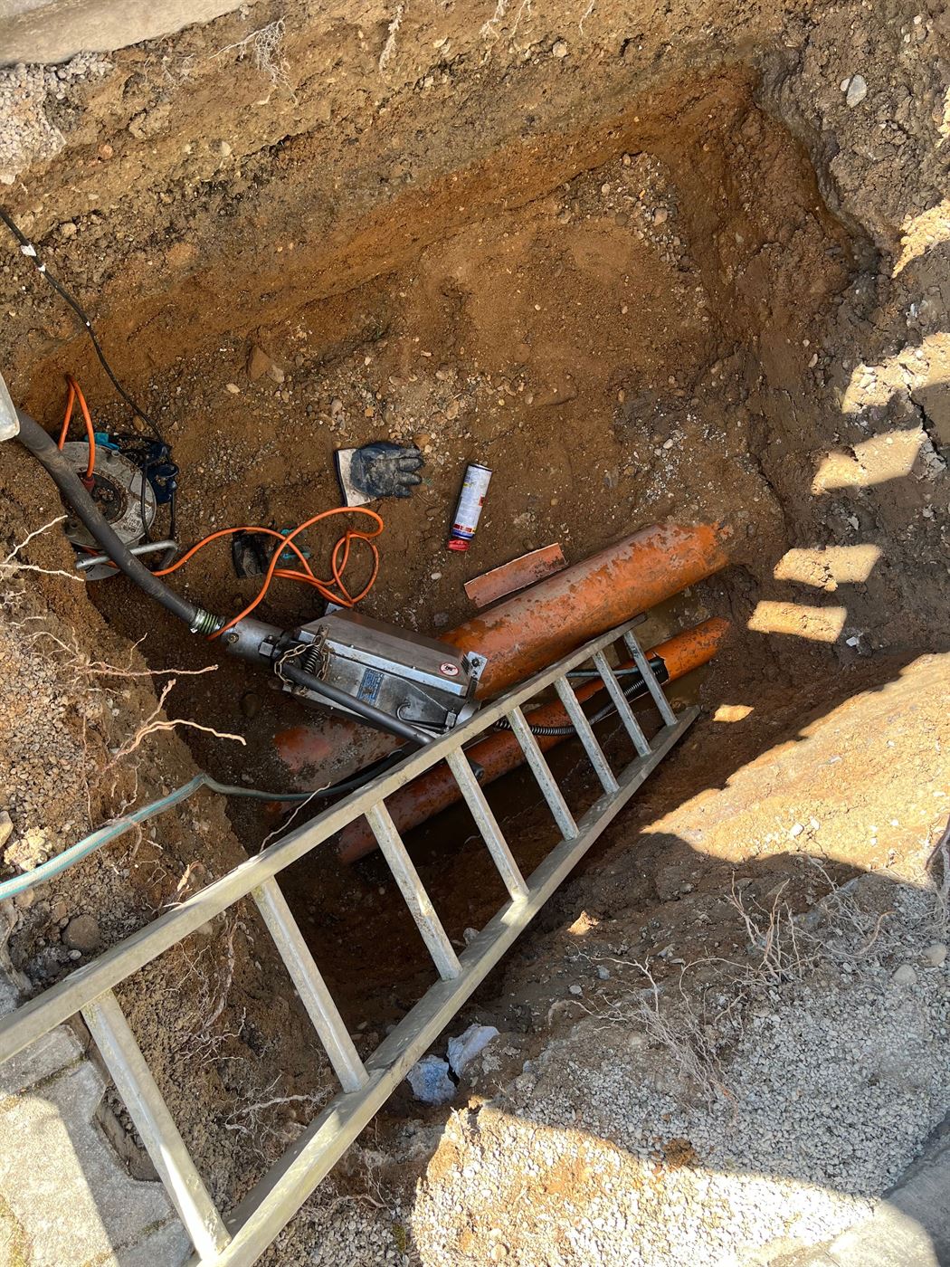 Aufgegrabene Baustelle mit freigelegtem KG-Rohr im Erdreich